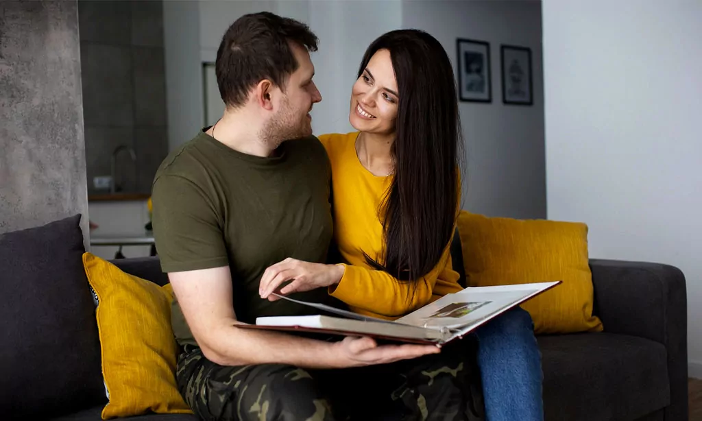 A happy couple sits together on a cozy couch