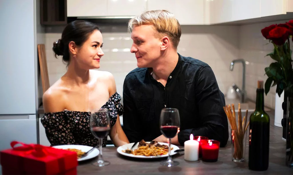 Romantic candlelit dinner with wine, flowers, and a couple sharing a cozy, intimate moment